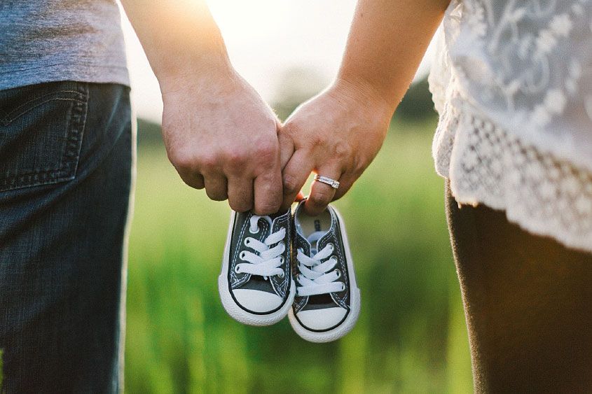 Man and Woman Holding Baby Shoes in Hands